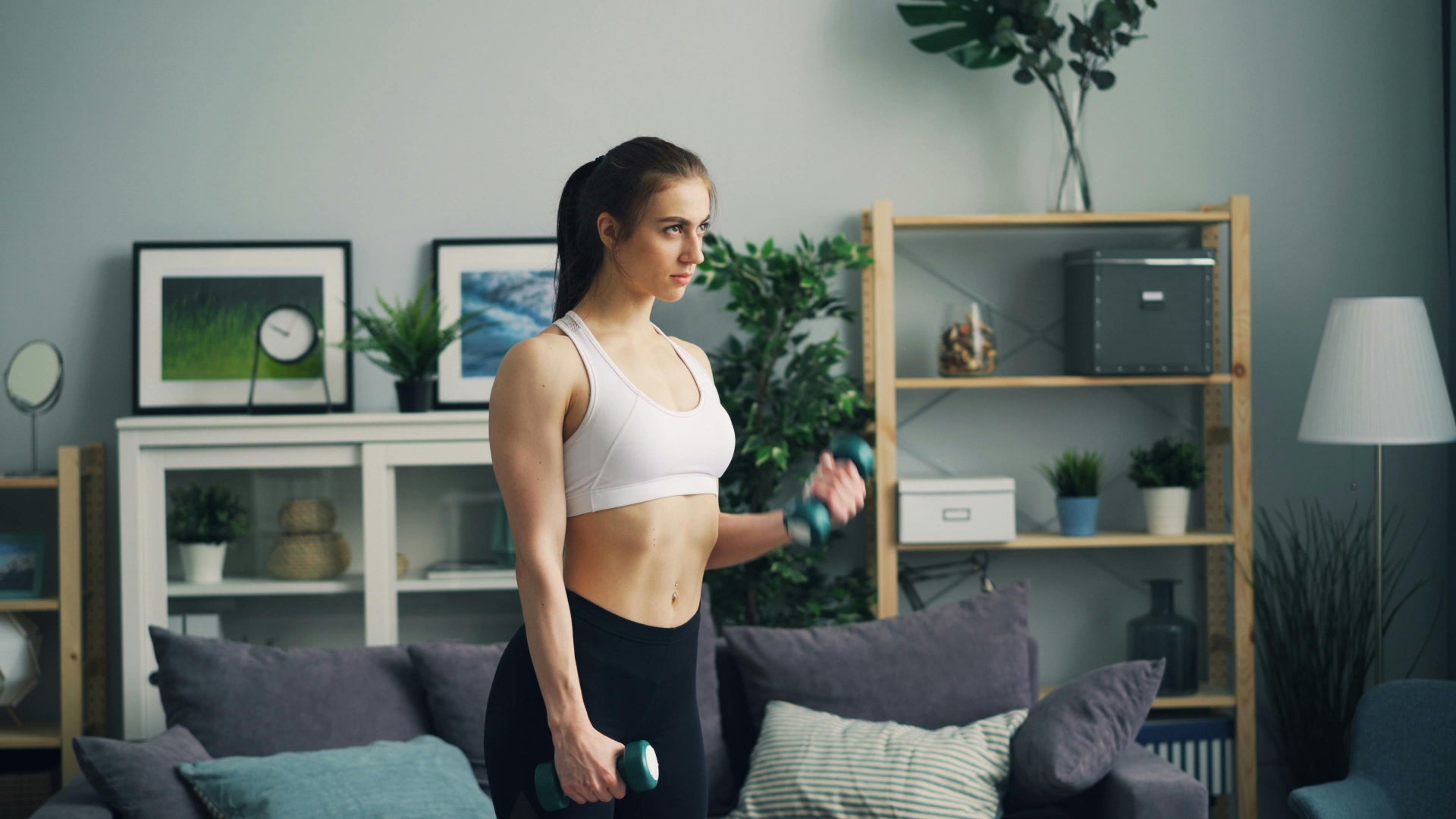 Woman exercising with dumbbells in a living room setting